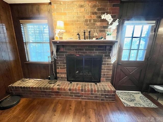 details with hardwood / wood-style floors, wood walls, and a brick fireplace