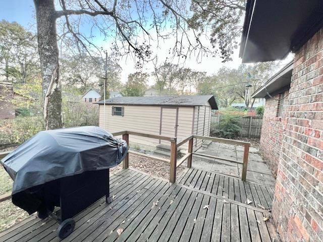 wooden deck featuring a shed and a grill