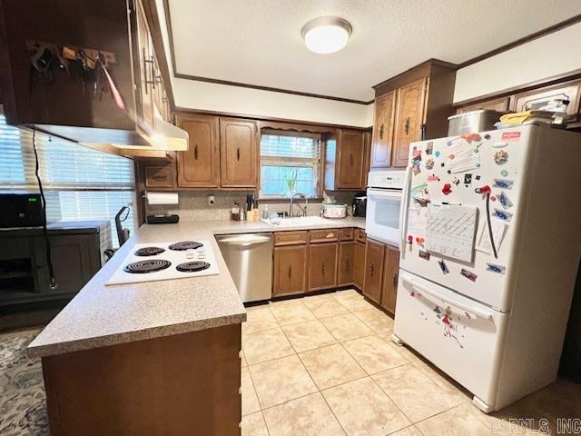 kitchen with white appliances, exhaust hood, sink, light tile patterned floors, and ornamental molding