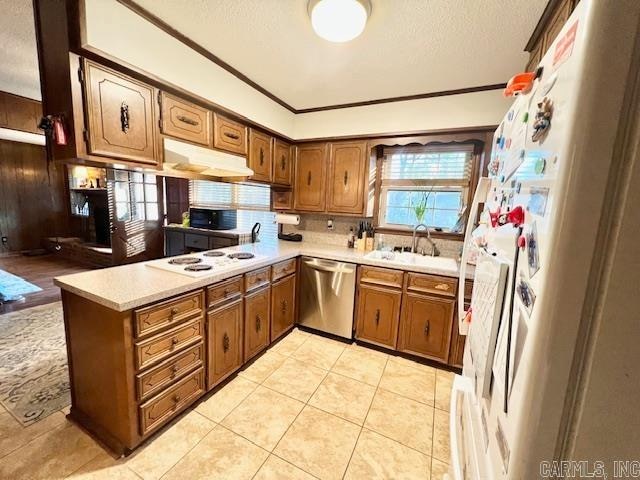 kitchen featuring sink, kitchen peninsula, crown molding, white appliances, and light tile patterned flooring