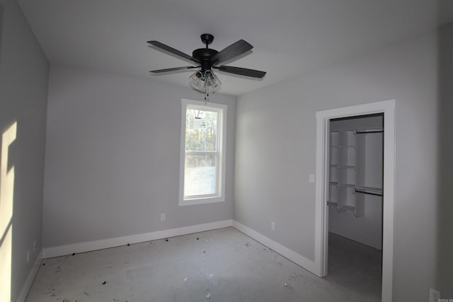 unfurnished bedroom featuring a spacious closet, a closet, and ceiling fan