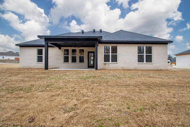 rear view of property featuring ceiling fan, a patio area, and a lawn