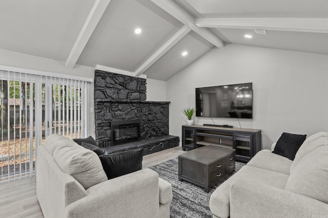 living room with lofted ceiling with beams, a stone fireplace, and light wood-type flooring