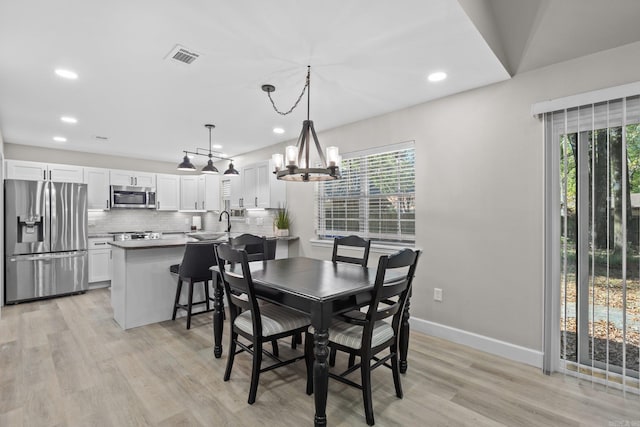 dining area with a chandelier, light hardwood / wood-style flooring, and a healthy amount of sunlight