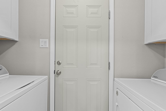 clothes washing area with washer and dryer and cabinets