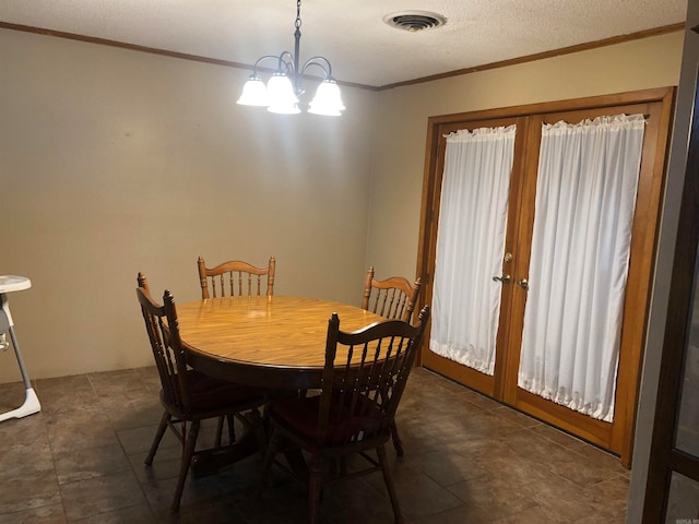 dining room featuring french doors, ornamental molding, a textured ceiling, and an inviting chandelier