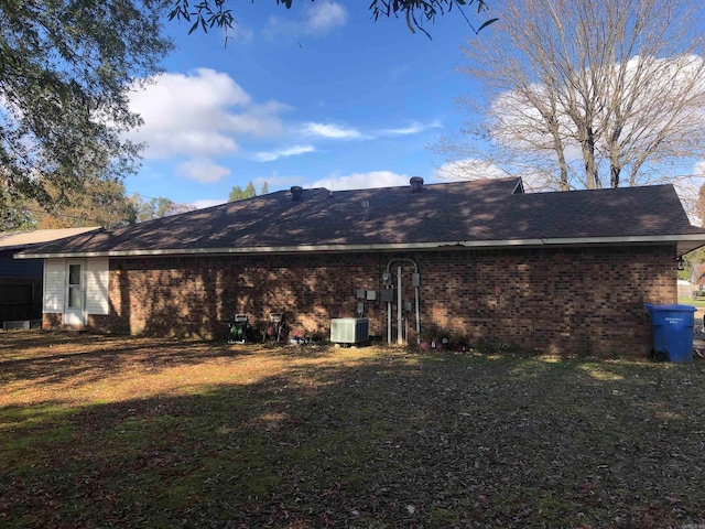 rear view of property with a lawn and central air condition unit