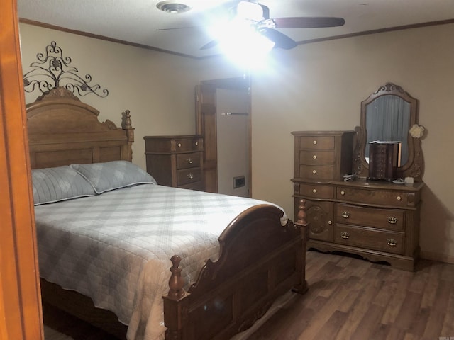 bedroom featuring dark hardwood / wood-style flooring, ceiling fan, and ornamental molding