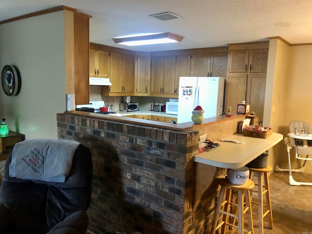 kitchen featuring kitchen peninsula, a kitchen bar, white appliances, a textured ceiling, and crown molding