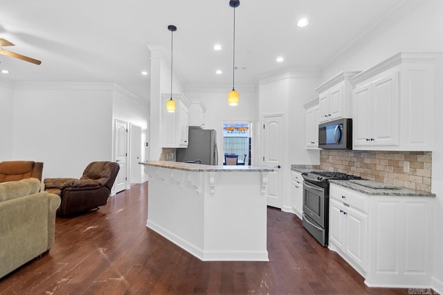 kitchen with white cabinetry, stainless steel appliances, hanging light fixtures, and dark wood-type flooring