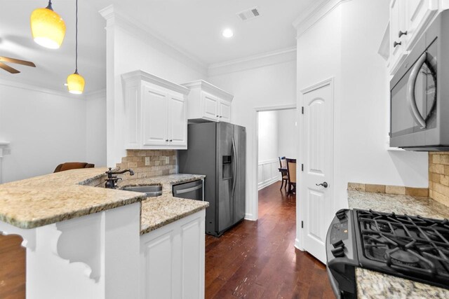 kitchen featuring appliances with stainless steel finishes, pendant lighting, white cabinetry, and a breakfast bar area