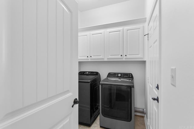 washroom with washing machine and clothes dryer, light tile patterned flooring, and cabinets