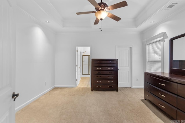 carpeted bedroom featuring a tray ceiling, ceiling fan, ornamental molding, and ensuite bathroom