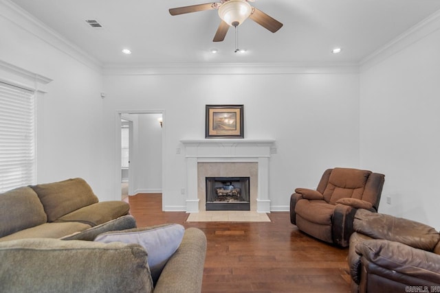 living room with a tile fireplace, ceiling fan, wood-type flooring, and ornamental molding