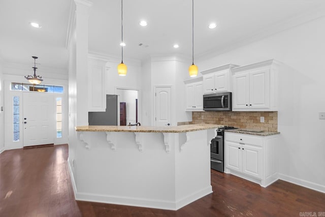 kitchen featuring white cabinets, a breakfast bar, decorative light fixtures, and appliances with stainless steel finishes