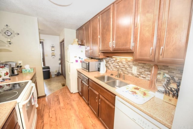 kitchen with light wood-type flooring, white appliances, sink, and tasteful backsplash