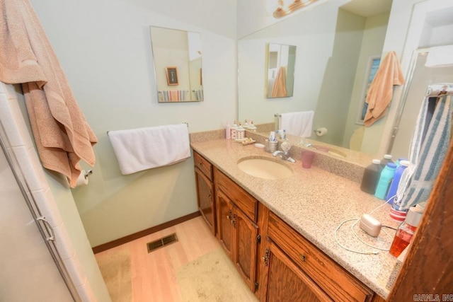 bathroom with vanity, an enclosed shower, and wood-type flooring