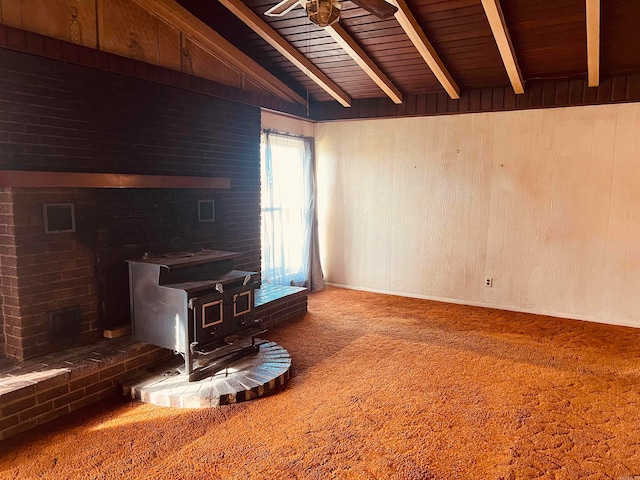 unfurnished living room with a wood stove, wood walls, carpet floors, and wooden ceiling