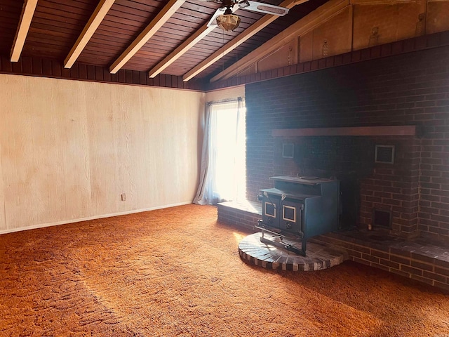 unfurnished living room featuring a wood stove, wooden walls, lofted ceiling with beams, and wooden ceiling