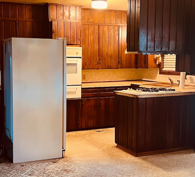 kitchen with wood walls, white fridge, and light colored carpet