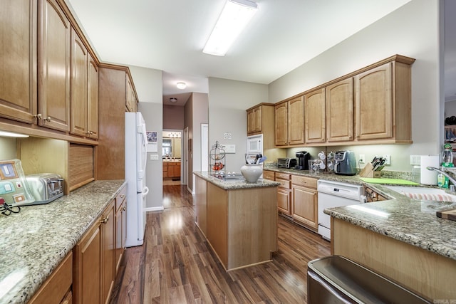 kitchen with light stone countertops, white appliances, dark wood-type flooring, sink, and a kitchen island