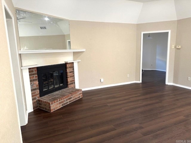 unfurnished living room featuring vaulted ceiling, dark hardwood / wood-style floors, and a brick fireplace