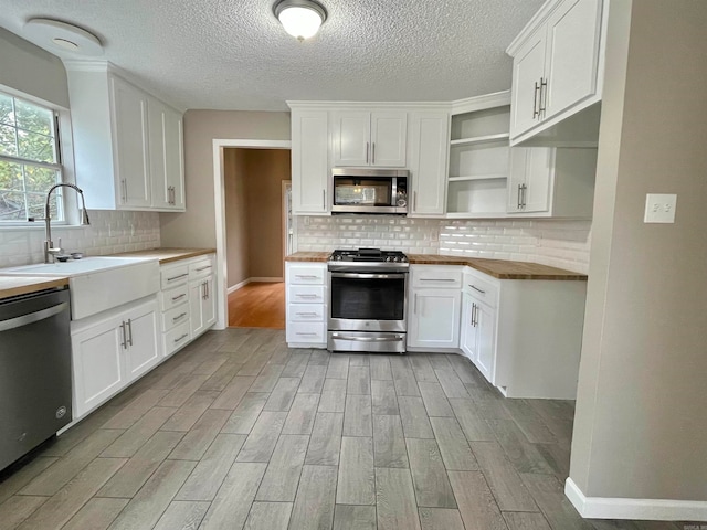 kitchen with backsplash, white cabinets, sink, light hardwood / wood-style floors, and stainless steel appliances