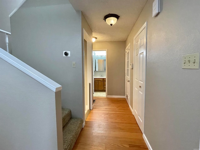 hallway featuring a textured ceiling and light wood-type flooring