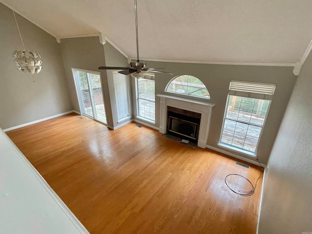 unfurnished living room featuring ceiling fan with notable chandelier, light wood-type flooring, and a wealth of natural light