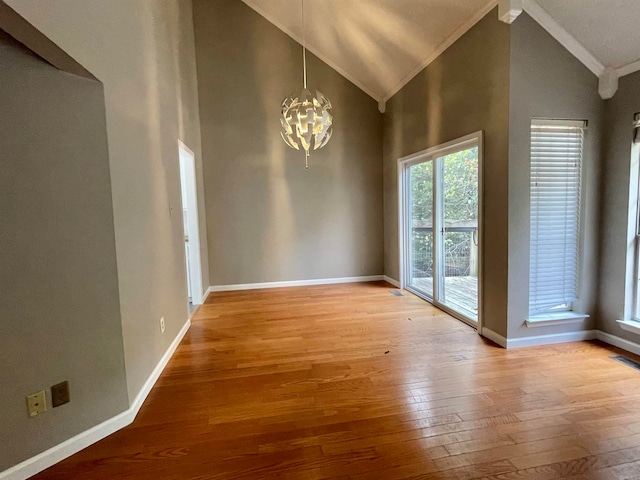 unfurnished dining area featuring hardwood / wood-style floors, high vaulted ceiling, ornamental molding, and a notable chandelier