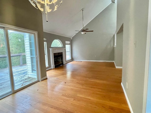 unfurnished living room with high vaulted ceiling, ceiling fan with notable chandelier, and light wood-type flooring