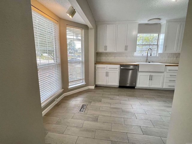 kitchen with white cabinets, tasteful backsplash, a textured ceiling, sink, and dishwasher