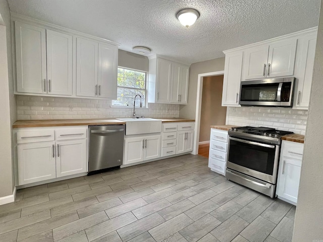 kitchen featuring butcher block countertops, sink, white cabinetry, and stainless steel appliances