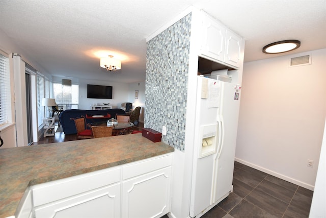 kitchen featuring white refrigerator with ice dispenser, a textured ceiling, and white cabinetry