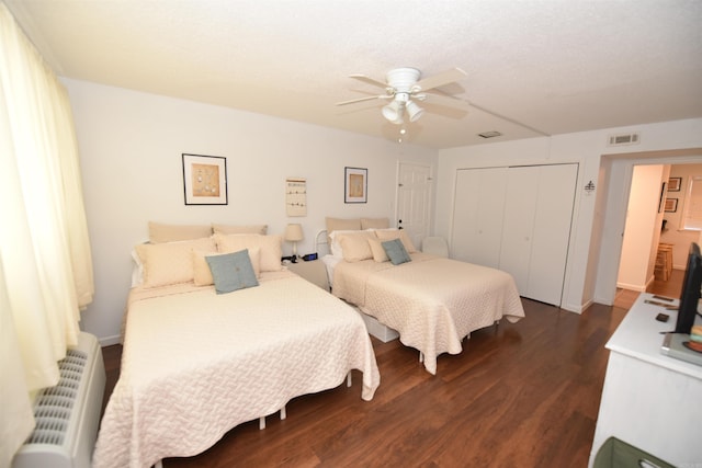 bedroom with ceiling fan, dark hardwood / wood-style flooring, radiator, and a closet