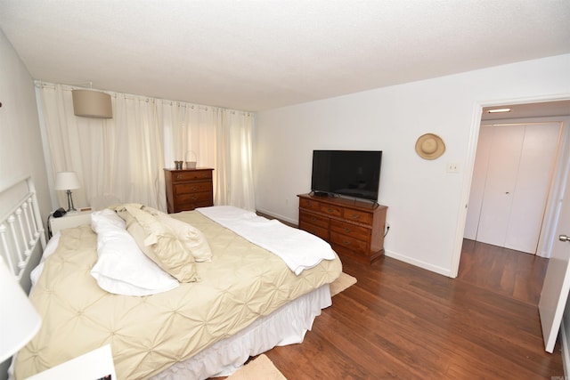 bedroom with dark hardwood / wood-style floors and a closet