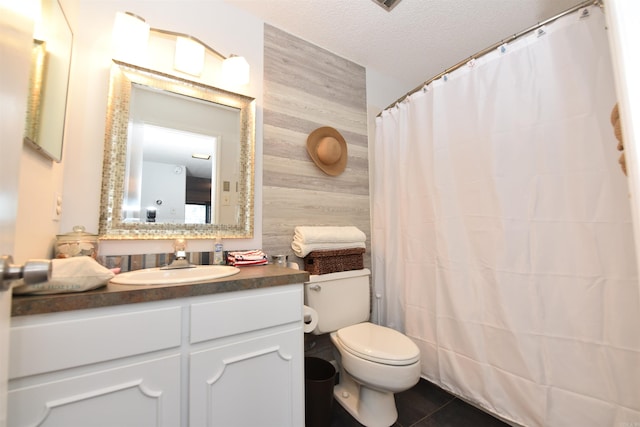 bathroom featuring vanity, wood walls, tile patterned flooring, toilet, and a textured ceiling