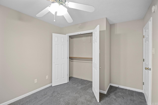 unfurnished bedroom with ceiling fan, a closet, and dark colored carpet