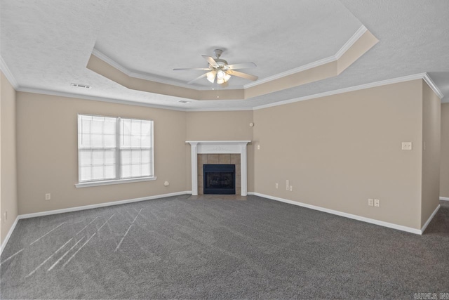 unfurnished living room with ceiling fan, ornamental molding, a fireplace, and a tray ceiling