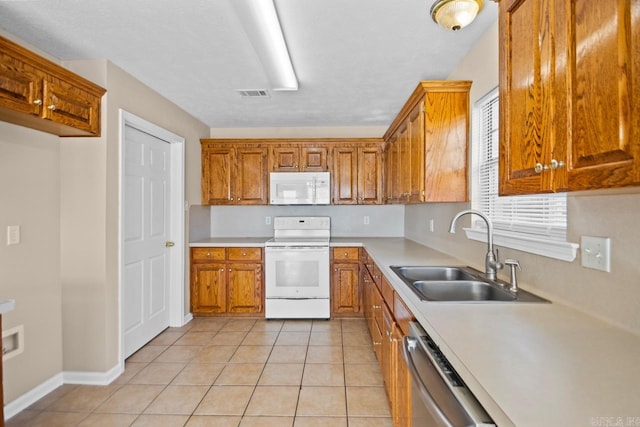 kitchen with light tile patterned flooring, white appliances, and sink