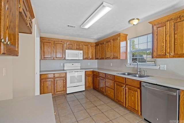 kitchen featuring a textured ceiling, white appliances, sink, and light tile patterned floors