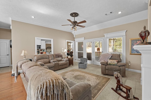 living room with ceiling fan, ornamental molding, a textured ceiling, and light carpet