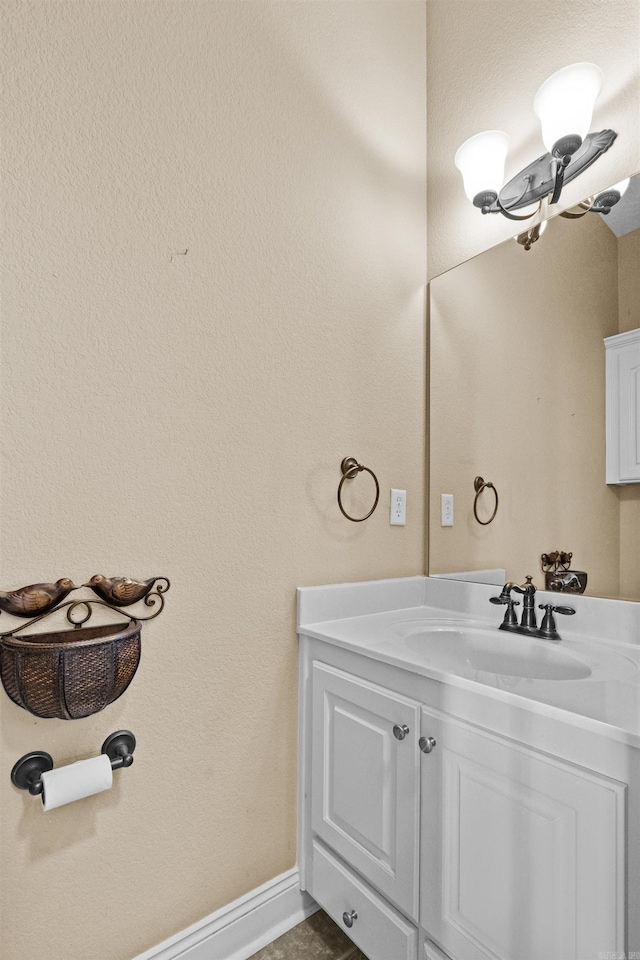 bathroom with a notable chandelier, vanity, and baseboards