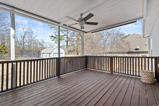 wooden deck featuring an outbuilding, a trampoline, and ceiling fan