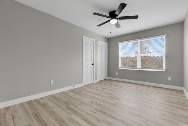 unfurnished bedroom with ceiling fan, multiple closets, and light hardwood / wood-style flooring