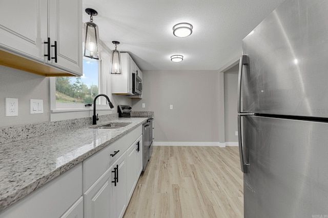 kitchen with hanging light fixtures, white cabinets, stainless steel appliances, and sink