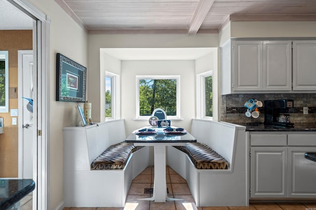 tiled dining space with beam ceiling, breakfast area, and wood ceiling