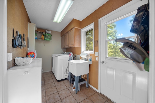 clothes washing area featuring cabinets, light tile patterned flooring, washing machine and dryer, and a textured ceiling