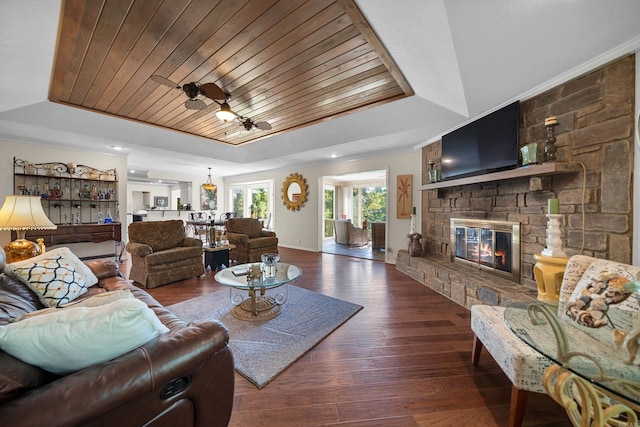 living room with ceiling fan, wooden ceiling, dark wood-type flooring, a raised ceiling, and a fireplace