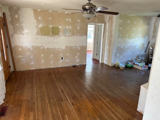 unfurnished room featuring a textured ceiling, ceiling fan, and dark wood-type flooring